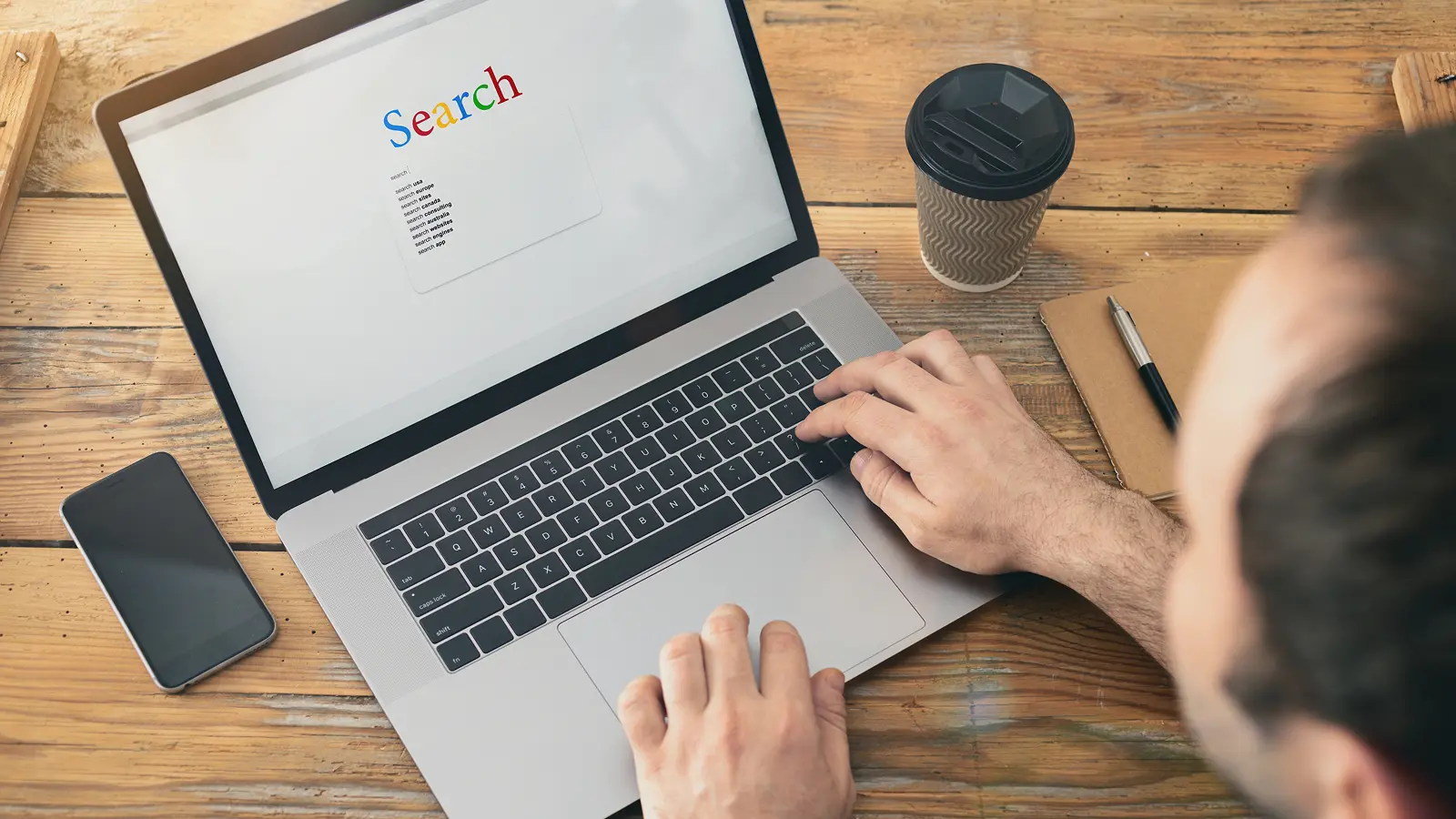 Person using a laptop to search online, representing local search behavior for car dealerships.