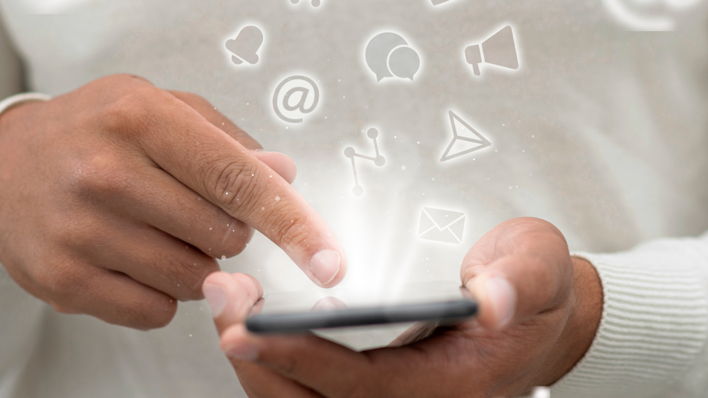 Close-up of hands using a smartphone with glowing digital icons representing social media, messaging, email, and notifications.